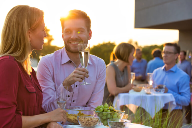 Smiling business colleagues standing at table during rooftop party