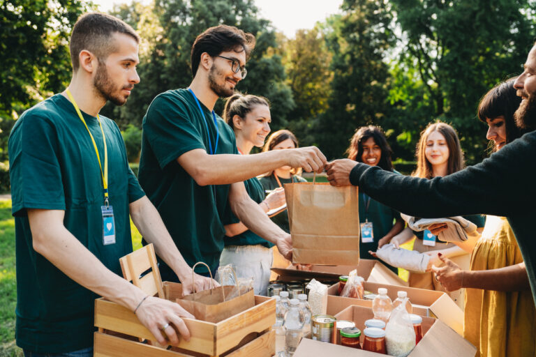 A couple is taking a bag of food at the food and clothes bank. Volunteers are working together at the humanitarian aid project.